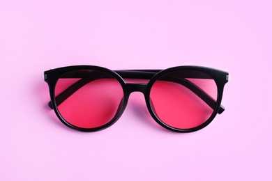 Stylish sunglasses on light violet background, top view