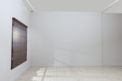 Empty room with white walls, large window and wooden floor