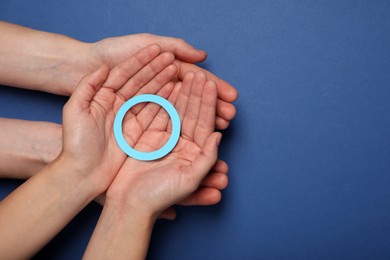 People showing blue paper circle as World Diabetes Day symbol on color background, top view with space for text