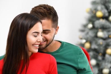 Happy young couple near Christmas tree at home