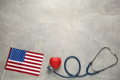 American flag, heart and stethoscope on light grey table, flat lay. Space for text