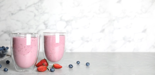 Tasty milk shakes and fresh berries on grey marble table. Space for text