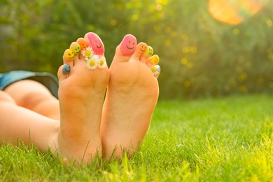 Teenage girl with chamomiles and smiling faces drawn on toes outdoors, closeup. Space for text