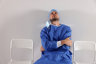 Exhausted doctor sitting on chair near grey wall