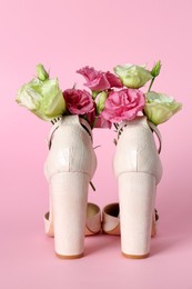 Stylish women's high heeled shoes with beautiful flowers on pink background