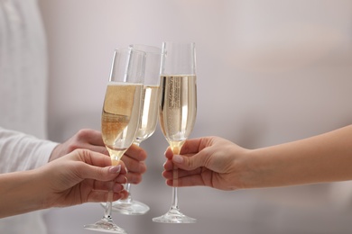People clinking glasses of champagne against blurred background, closeup