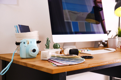 Photo of Digital camera and color palette on table in studio. Modern designer's workplace