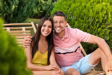 Image of Happy couple resting in deck chairs outdoors