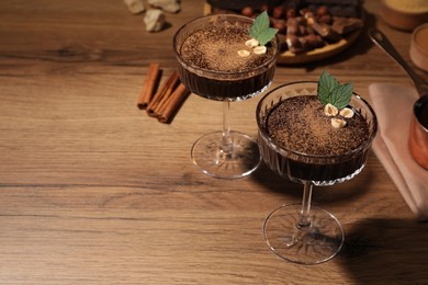 Photo of Dessert bowls of delicious hot chocolate and ingredients on wooden table. Space for text