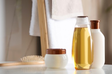 Shampoo, conditioner and hair mask near brush on white table in bathroom, space for text