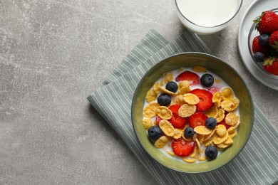 Corn flakes with berries in bowl served on grey table, flat lay. Space for text