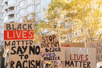 Protesters demonstrating different anti racism slogans outdoors. People holding signs with phrases, closeup view