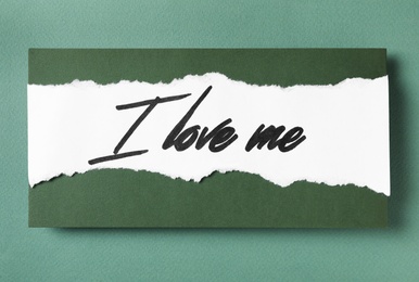 Paper with handwritten phrase I Love Me on green background, top view