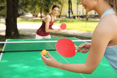 Young women playing ping pong in park, closeup