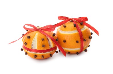 Pomander balls with red ribbons made of fresh tangerines and cloves on white background