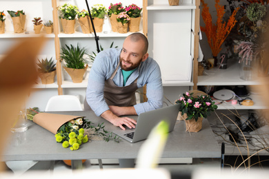Professional male florist using laptop at workplace