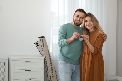 Happy young couple with key in new house. Space for text