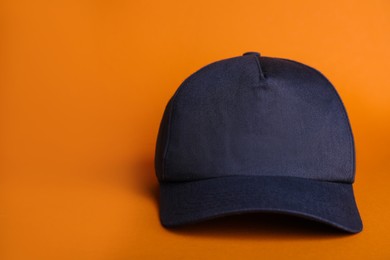 Baseball cap on orange background, space for text
