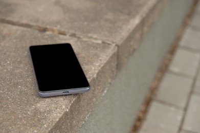 Smartphone on street curb outdoors. Lost and found