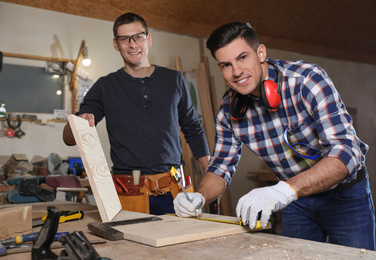 Professional carpenters working with wooden boards in workshop