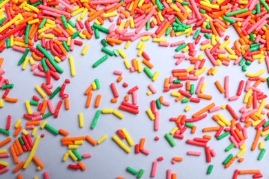 Colorful sprinkles on light grey background, flat lay. Confectionery decor