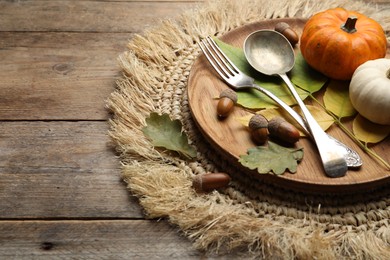 Photo of Autumn table setting with pumpkins and fallen leaves on wooden background, closeup. Space for text
