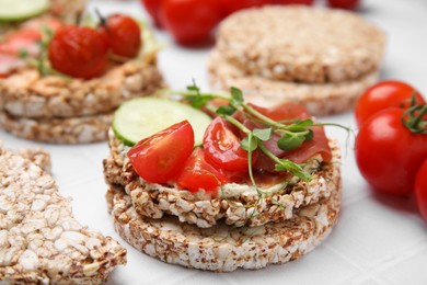 Crunchy buckwheat cakes with prosciutto, pieces of tomato and cucumber slice on white table, closeup