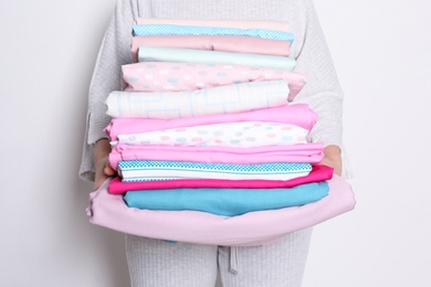 Woman holding stack of clean bed linens on white background, closeup