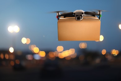 Modern drone with carton box flying above night city. Delivery service 