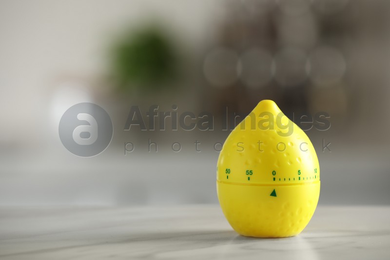 Kitchen timer in shape of lemon on white table against blurred background. Space for text