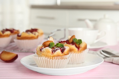 Delicious cupcakes with plums on pink wooden table, closeup