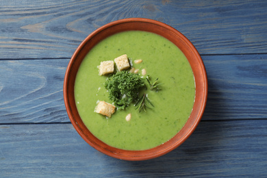 Tasty kale soup with croutons on blue wooden table, top view
