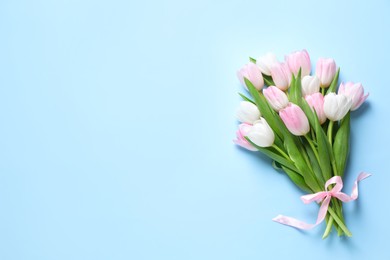 Beautiful pink spring tulips on light blue background, top view. Space for text