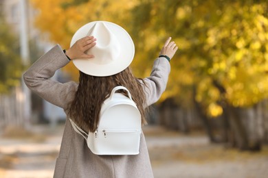 Young woman with stylish white backpack on city street, back view
