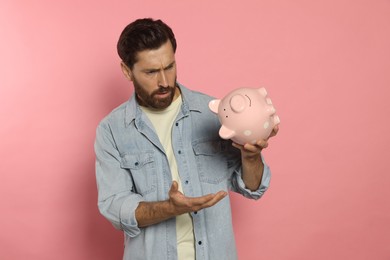 Photo of Man with ceramic piggy bank on pale pink background