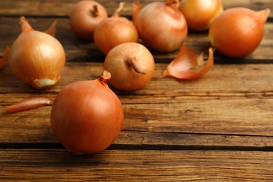 Many ripe onion bulbs on wooden table