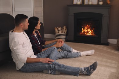 Photo of Lovely couple spending time together near fireplace at home