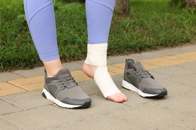 Photo of Woman with foot wrapped in medical bandage on outdoors, closeup