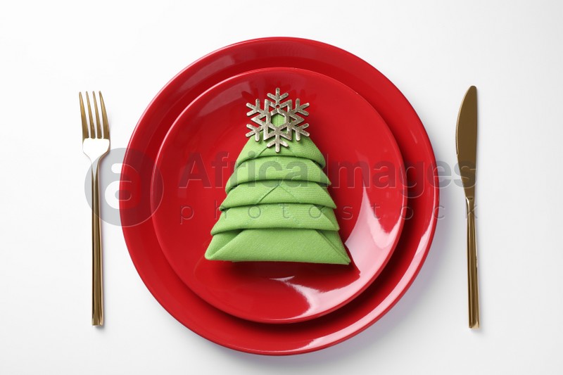 Festive table setting with green napkin folded in shape of Christmas tree on white background, top view