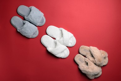 Different soft fluffy slippers on red background, flat lay