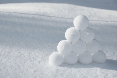 Pyramid of perfect snowballs on snow outdoors. Space for text