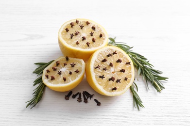 Lemons with cloves and fresh rosemary on white wooden table. Natural homemade repellent