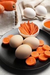 Photo of Naturally painted Easter eggs on light grey table, closeup. Carrot used for coloring