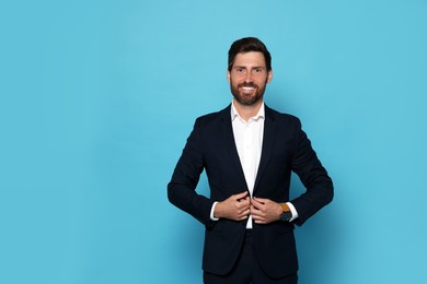 Portrait of smiling bearded man in suit on light blue background