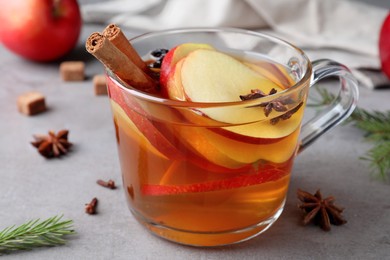 Aromatic hot mulled cider on grey table, closeup