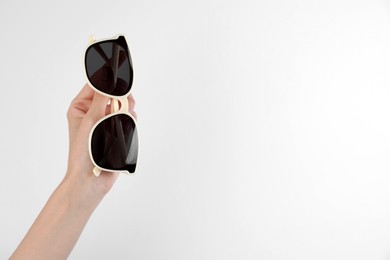 Photo of Woman holding stylish sunglasses on white background, closeup. Space for text