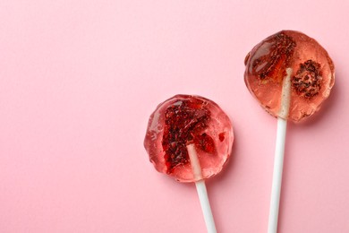 Sweet colorful lollipops with berries on pink background, flat lay. Space for text