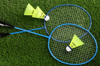 Badminton rackets and shuttlecocks on green grass outdoors, flat lay