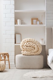 Soft chunky knit blanket and pouf in stylish room interior