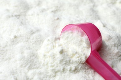 Powdered infant formula and scoop, closeup with space for text. Baby milk